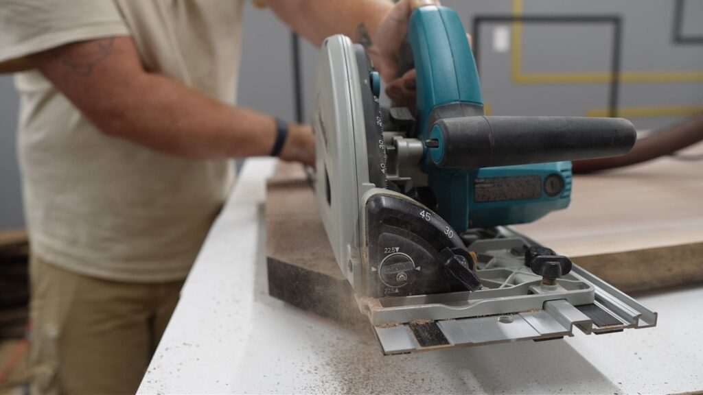 Curtis running a track saw through walnut with sawdust flying, an action shot in the workshop.