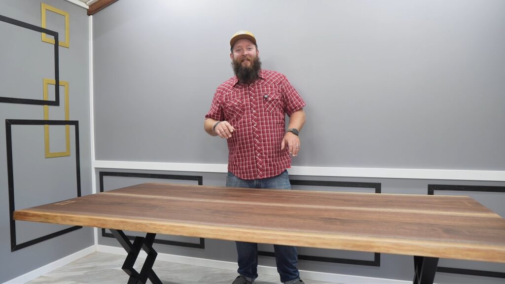 Curtis in a red plaid shirt standing behind the finished walnut dining table.